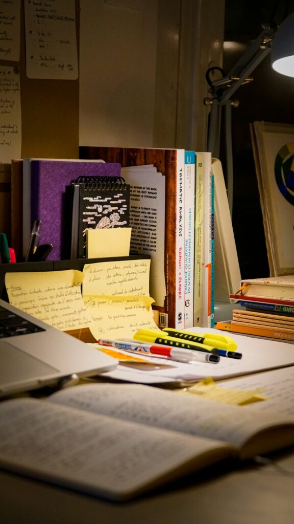 A study desk with an open book, laptop, and handwritten notes, documentary style.