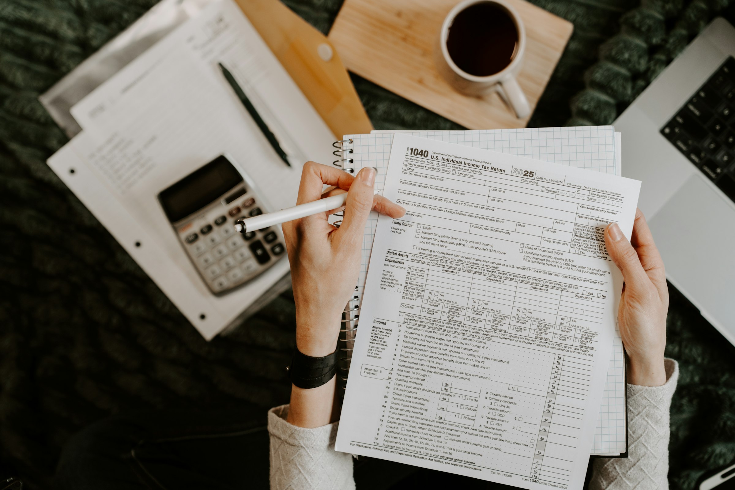 A student reviews documents and a laptop at a desk while preparing a study abroad application. Photo by Kelly Sikkema on Unsplash.