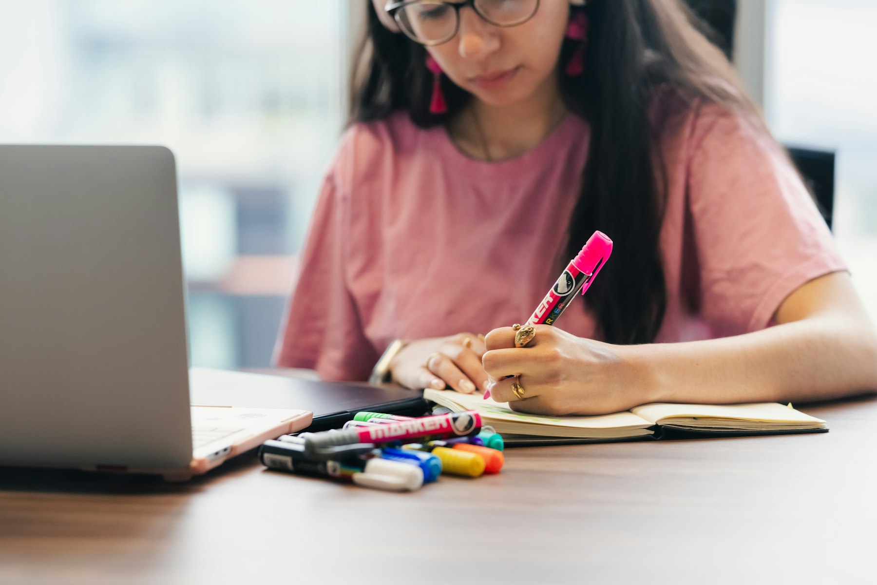 Student studying at a laptop with notes at an ordinary home desk